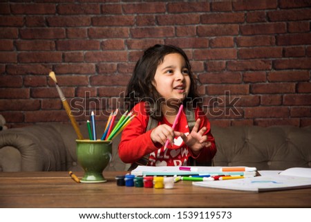 Indian small girl drawing / Painting with colours over paper, selective focus