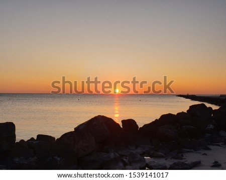 A beautiful sunset on the beach with white sand and some rocks in Vada, Mazzanta, Italy on a beautiful summer afternoon - Romantic landscape full of colours