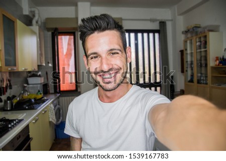 Photo of handsome man taking a selfie at home smiling on the camera