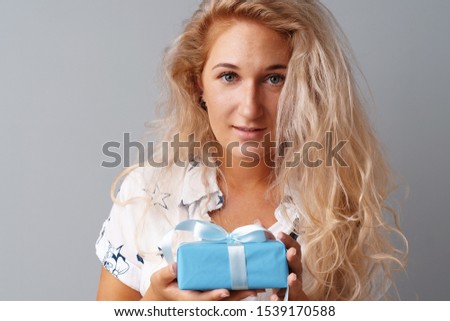 Nice woman holding a blue gift box in her hands