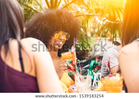 Portrait of a happy and smiling black woman having fun with friends drinking a cocktail outdoor
