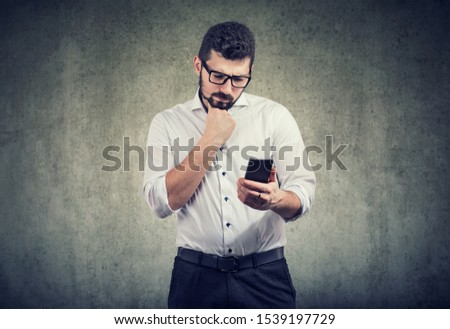 Confused young man looking at his cellphone 