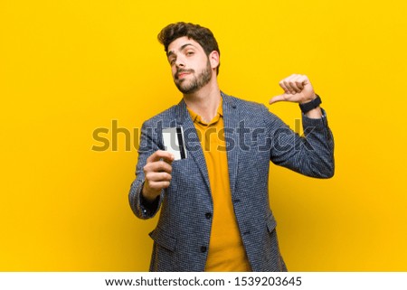 young handsome man with a credit card against orange background