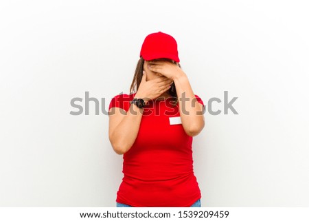 delivery woman covering face with both hands saying no to the camera! refusing pictures or forbidding photos against white background