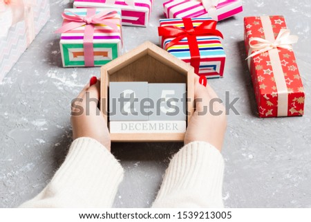Top view of female hands holding a calendar on cement background. The twenty fifth of December. Holiday decorations. Christmas concept.