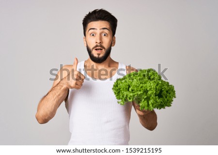 young man looking at the camera with a green salad in his hands