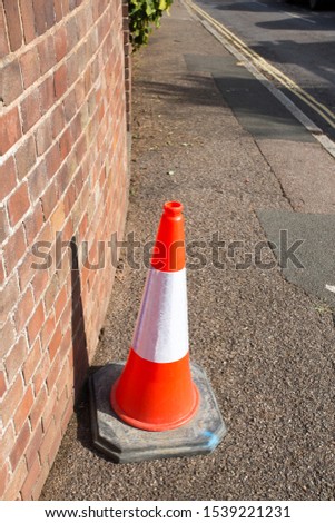 Street cone in orange and white stripes on a public path in england