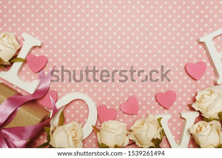 Love word alphabet and Gift box with roses bouquet with space copy on pink polka dot background