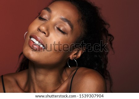 Picture of a pleased amazing african young woman isolated over red wall background.