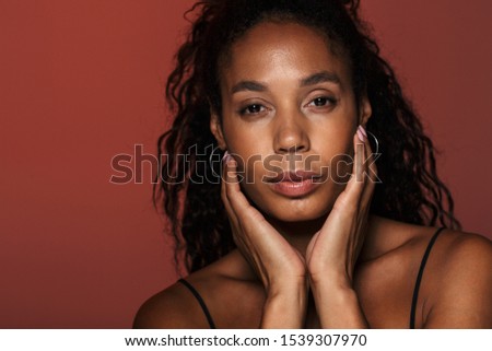 Picture of a beautiful african young woman isolated over red wall background.