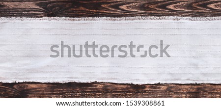 Grey fabric runner on an old wooden rustic table background with copy space. Top view.