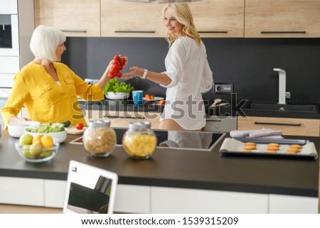 Smiling mother and daughter cooking dinner stock photo