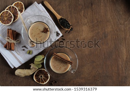 Masala chai tea on wooden background. Traditional Indian hot drink with spices. Top view, copy space.