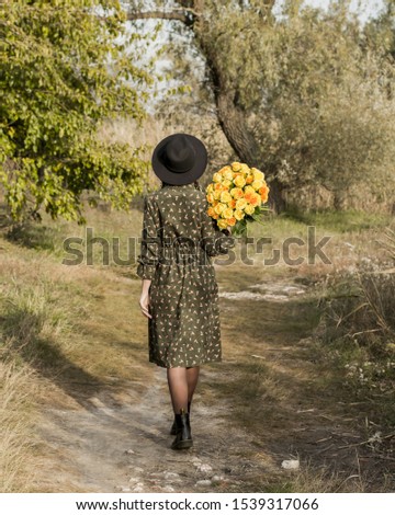Beautiful girl with a bouquet of yellow roses. Woman with model appearance in a hat. Pretty woman. Teenager girl in a black hat and roses.