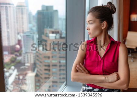 Office business woman worker taking a break pensive looking out the window thinking of future ideas. Asian businesswoman confident looking at skyline in city center in China, Asia.