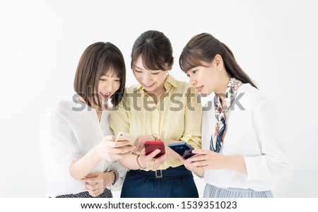 Group of asian girls showing smart phones each other.