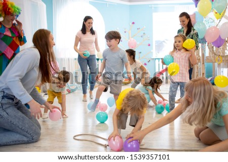 Happy kids and their moms entertain and have fun with color balloon on birthday party