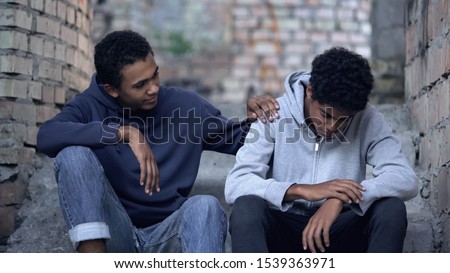 Afro-american teenager trying to make peace with friend, helping boy in need Royalty-Free Stock Photo #1539363971