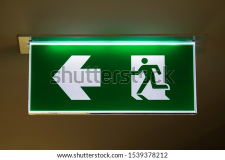 The real safety green sign symbol for go to the fire exit in dark background.