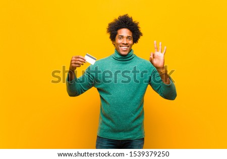 young african american man with a credit card against orange background