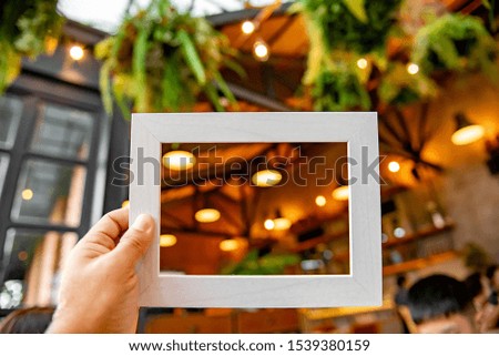 Man holding a white picture frame in the restaurant with copy space background.