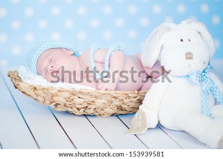Picture of a newborn baby curled up sleeping in a basket on a blanket