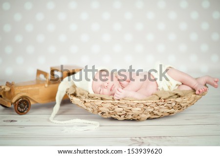 Picture of a newborn baby curled up sleeping in a basket