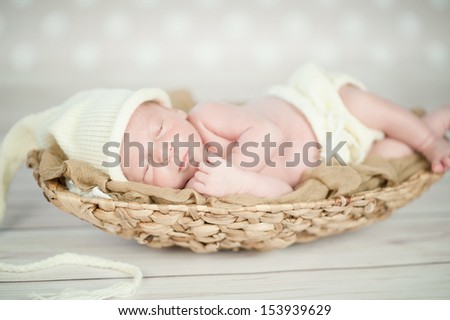 Picture of a newborn baby curled up sleeping in a basket