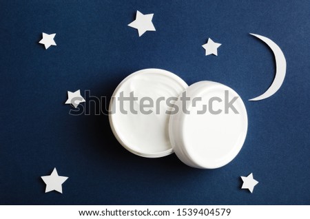 Cosmetic white container on night sky background top view. Skincare cosmetology product, night care concept. Organic cosmetics. Hand, face, body moisturizing cream jar. Women present idea Royalty-Free Stock Photo #1539404579