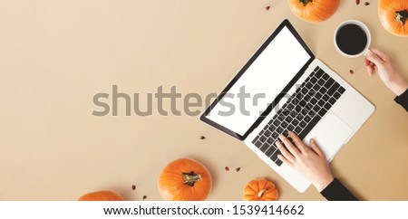 Person using a laptop computer with pumpkins - overhead view