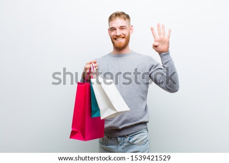 young red head man with shopping bags against white background