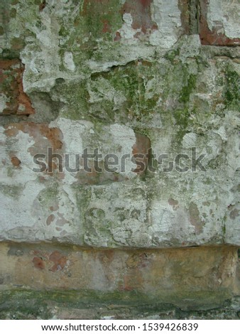Abstract background - an old wall of red ceramic brick damaged by flooding and covered with moss