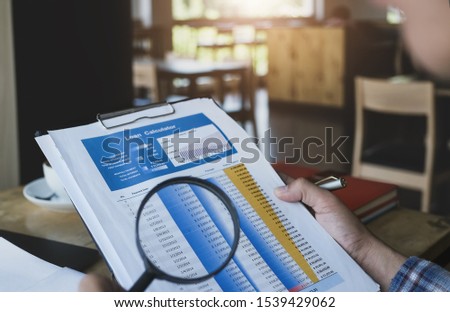 Business man using magnifying to review Loan Application  to audit loan numbers. audit and Check integrity before investment concept.
