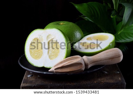 Sweetie cut into halves on a stone plate on the edge of the wooden table against black background