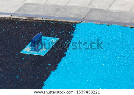 Rubber coating for playgrounds applied on the surface by a steel trowel. PDM rubber granules. Floor covering for sports. Rubber mulch for safety and injury prevention. Selective focus. Royalty-Free Stock Photo #1539438221