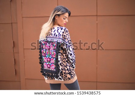 Young beautiful wearing animal print cardigan standing on backview at the town