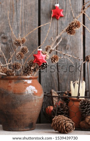 Winter composition, Christmas scene with branch of larch, glass star, crab apple in metal wicker basket, vintage style, daylight, vertical photo