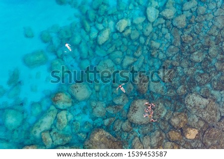 An aerial view of the beautiful Mediterranean sea, where you can se the rocky textured underwater corals and the clean turquoise water of blue lagoon Agia Napa and also some swimmers