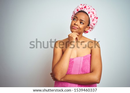 African american woman wearing pink shower towel after bath over isolated background with hand on chin thinking about question, pensive expression. Smiling with thoughtful face. Doubt concept.