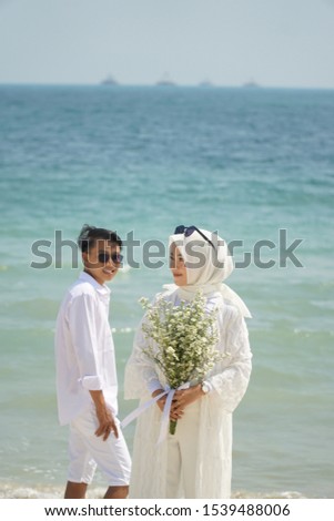 Asian couple wearing all white costume travel prewedding on the beach