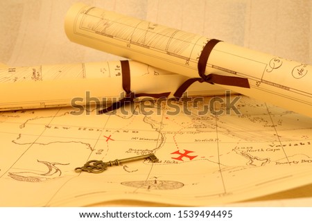An old fashioned map and key outlining a path to reveal buried treasure at the x marking the spot. Royalty-Free Stock Photo #1539494495