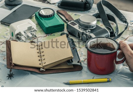 notebook with space for an inscription, tourist equipment, map with a cup of tea in hand