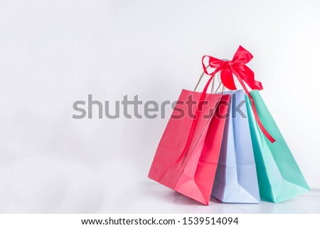 Christmas shopping and sale concept. Buying Christmas gifts. Pastel colored paper bags with xmas  and New Year gifts. On white background copy space