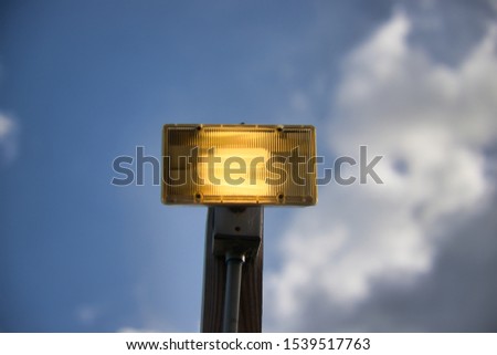 Outdoor light pole turned on in daylight Royalty-Free Stock Photo #1539517763