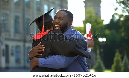 Cheerful father and graduating son hugging outdoor, study achievement, education Royalty-Free Stock Photo #1539525416