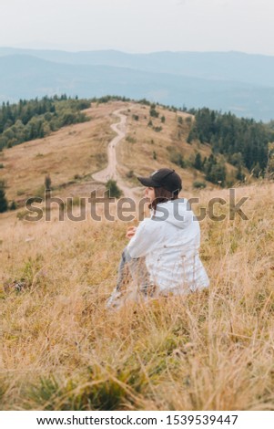 woman sitting on the ground looking at mountains hiking concept