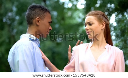 Confident teenage girl stopping boyfriend trying to kiss her, unrequited love