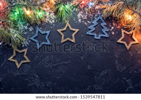 Picture of branches of spruce, Christmas blue toys, burning garlands on black background