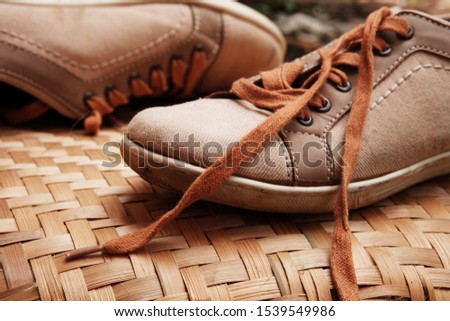 Stylish sneakers with bright orange shoelaces on traditional bamboo woven surfaces. Trendy shoes sport concept.