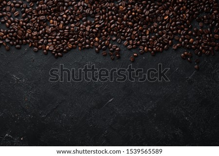Roasted coffee beans. On a black stone background. Top view. Free space for your text.